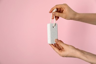Photo of Woman holding pumice stone on pink background, closeup. Space for text