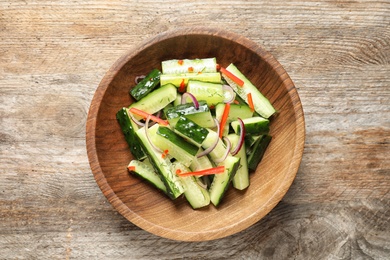 Photo of Plate with delicious cucumber salad on wooden background, top view