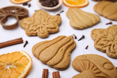 Photo of Different tasty cookies, spices and cutter on white table, closeup