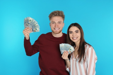 Photo of Young couple with money on color background