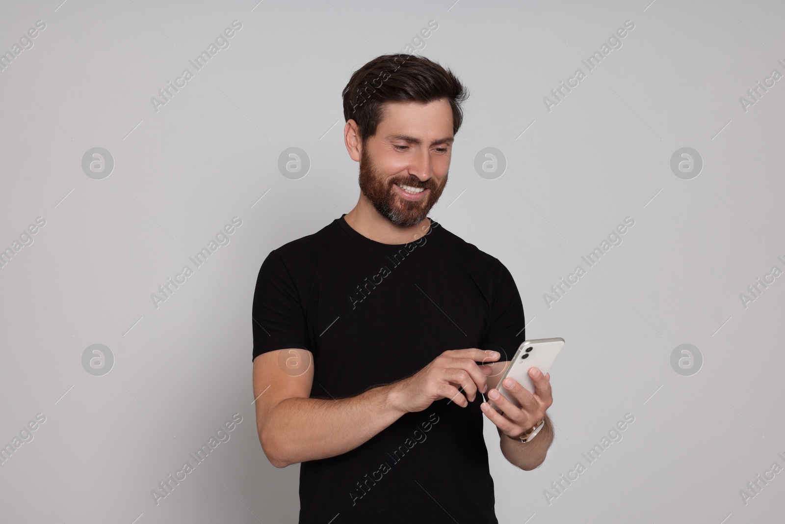 Photo of Happy man with smartphone on light background