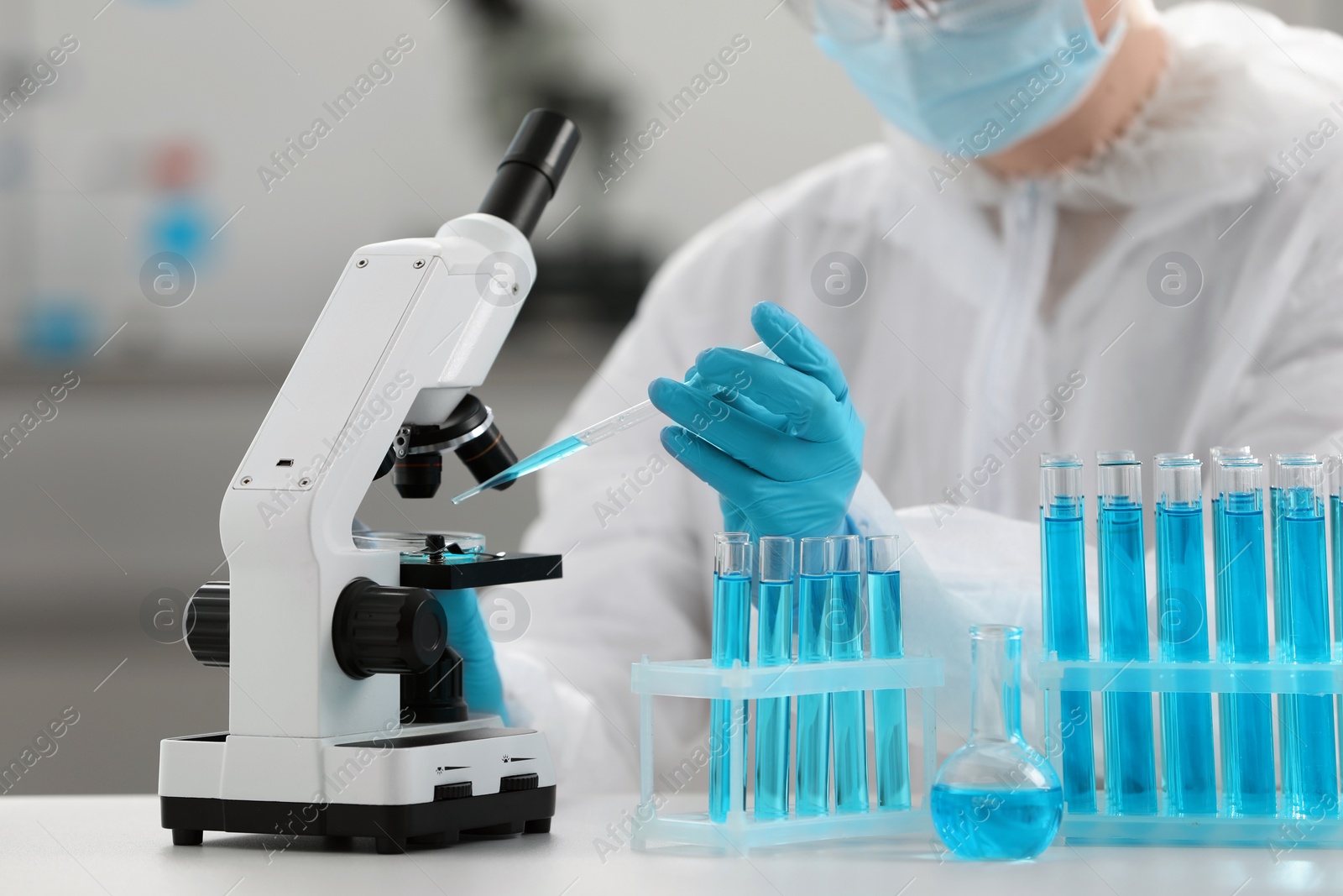 Photo of Scientist dripping sample onto Petri dish while working with microscope in laboratory, closeup