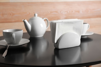 Photo of Ceramic napkin holder with paper tissues on served table. Tea time