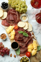 Photo of Charcuterie board. Delicious bresaola and other products served on white marble table, flat lay