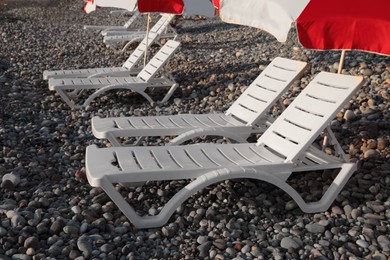 Empty sunbeds and umbrella on stone beach outdoors