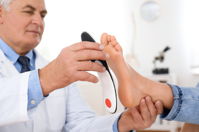 Male orthopedist fitting insole on patient's foot in clinic