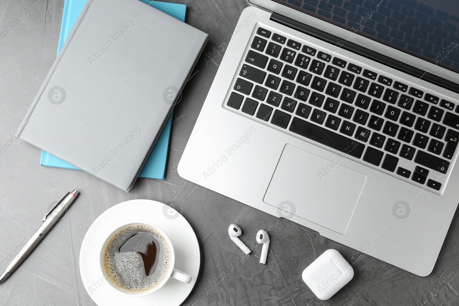 Photo of Flat lay composition with earphones and laptop on grey table