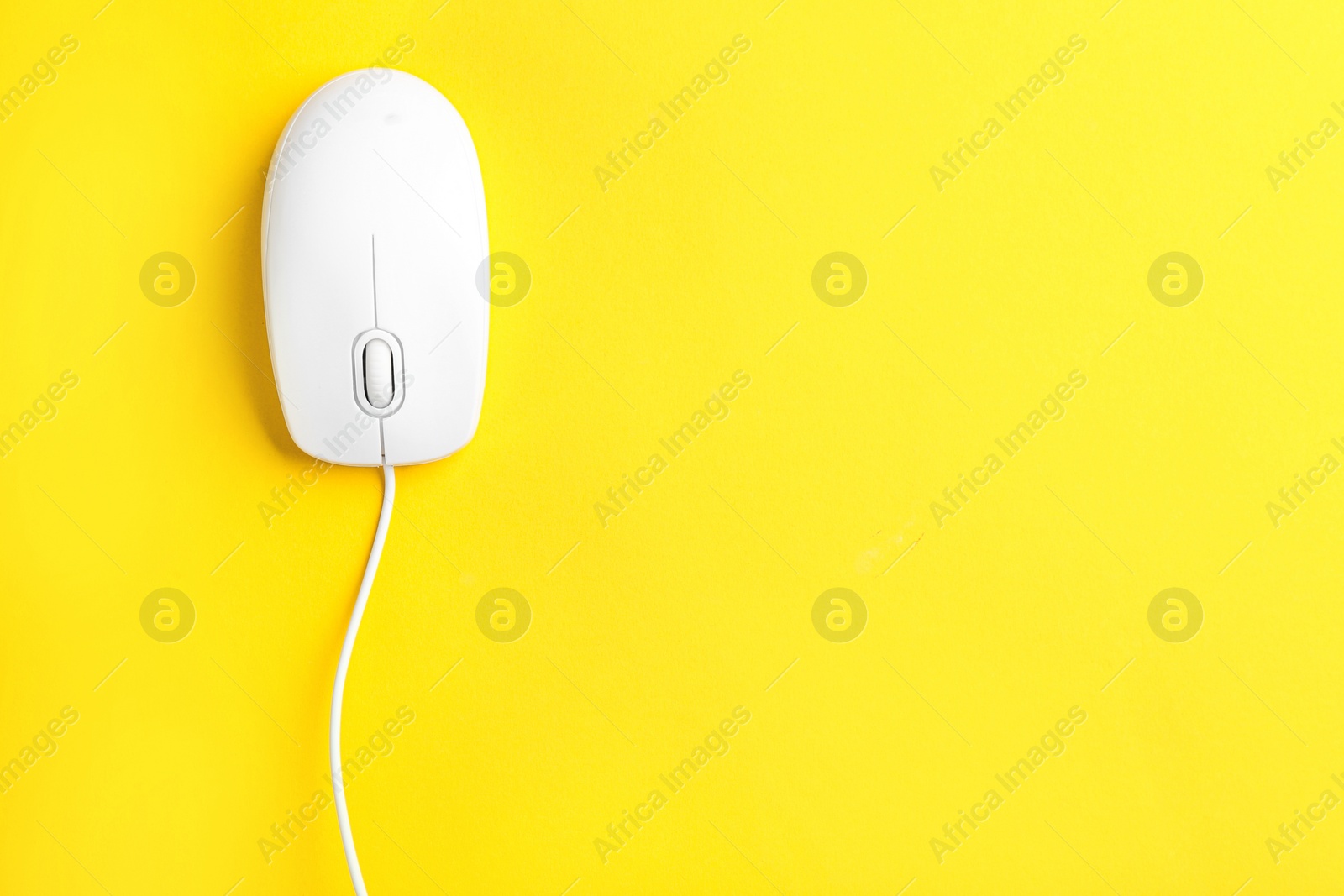 Photo of Modern wired optical mouse on yellow background, top view. Space for text