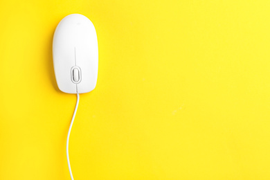 Photo of Modern wired optical mouse on yellow background, top view. Space for text