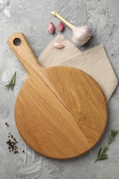 Photo of Cutting board, garlic, spices and rosemary on grey textured table, flat lay. Space for text