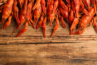 Delicious boiled crayfishes on wooden table, flat lay. Space for text