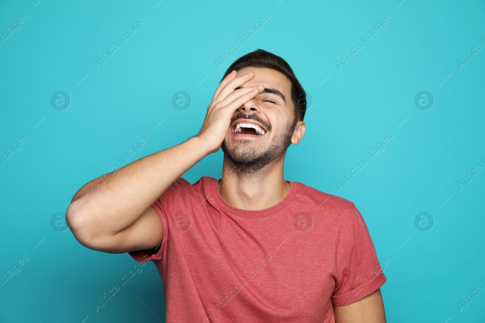 Photo of Handsome young man laughing against color background