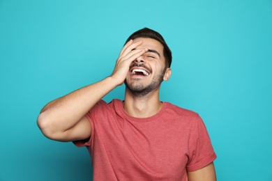 Handsome young man laughing against color background