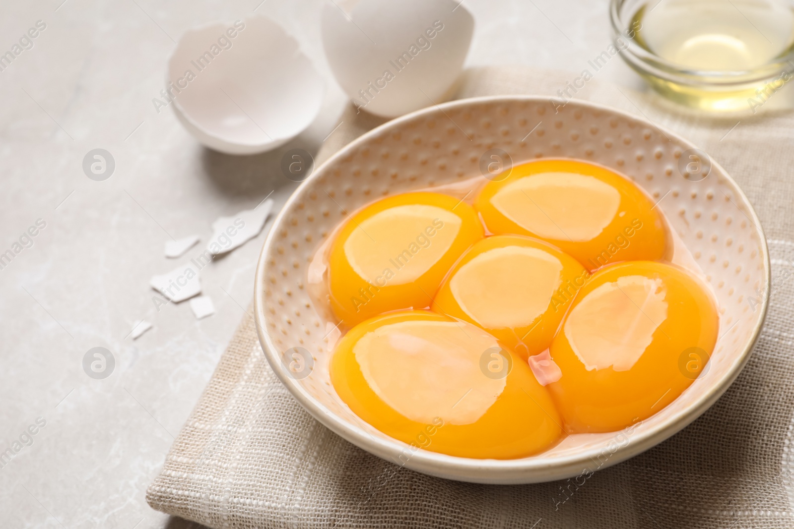 Photo of Bowl with raw egg yolks on light grey table