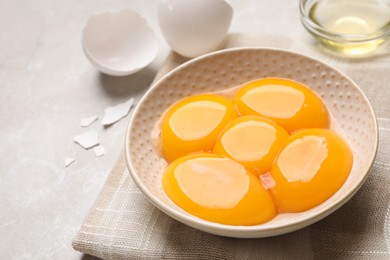 Bowl with raw egg yolks on light grey table