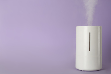 Modern air humidifier on violet background. Space for text