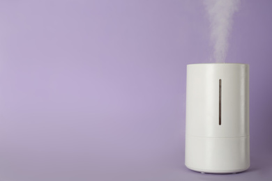 Photo of Modern air humidifier on violet background. Space for text