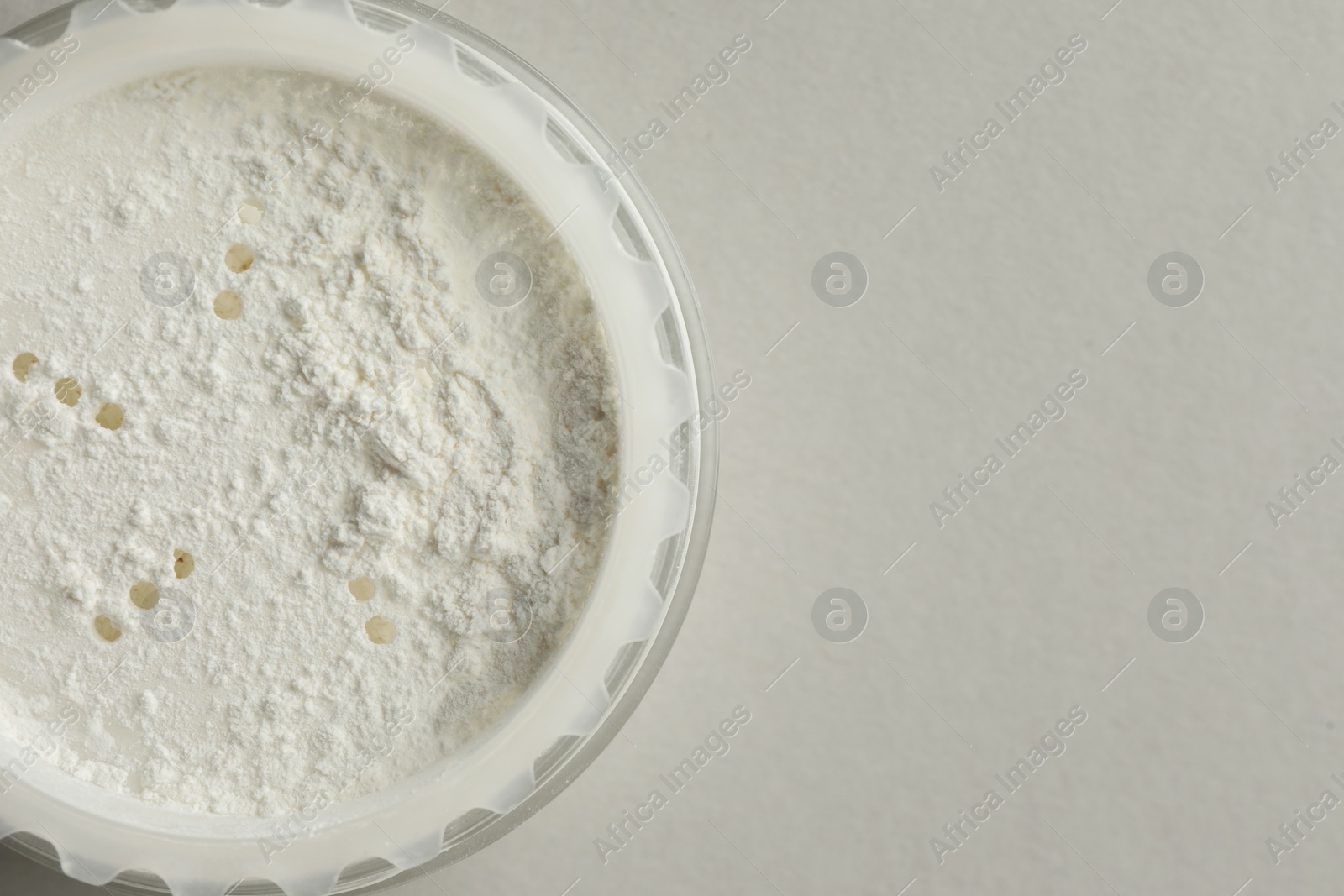 Photo of Rice loose face powder on light grey background, top view. Space for text