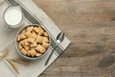 Photo of Bowl of sweet crispy corn pads and milk on wooden table, flat lay with space for text. Breakfast cereal