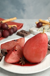 Photo of Plate of red wine poached pears on grey marble table against blue background