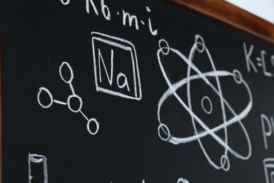 Different chemical formulas written with chalk on blackboard, closeup
