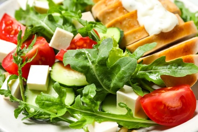 Photo of Delicious salad with chicken, arugula and tomatoes on plate, closeup