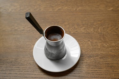 Jezve with fresh coffee on wooden table