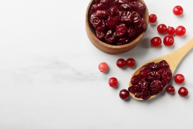 Photo of Tasty dried cranberries and fresh ones on white table, top view. Space for text