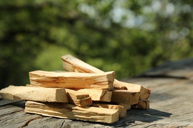 Photo of Palo santo sticks on wooden table outdoors, closeup