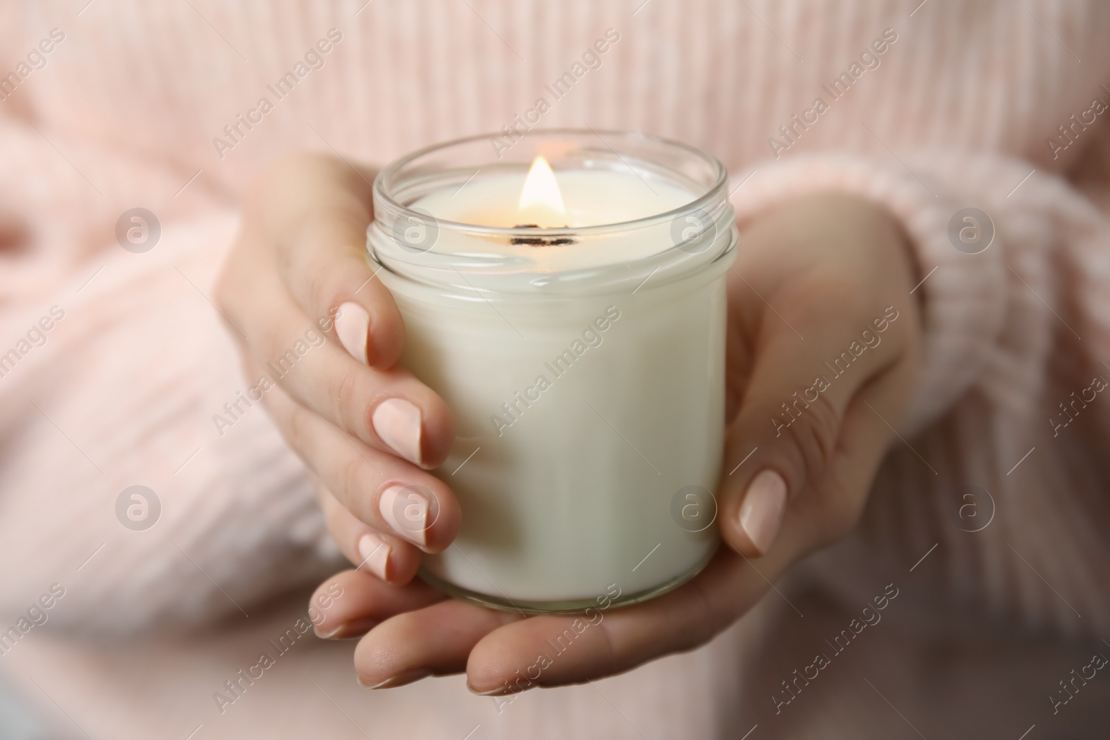 Photo of Woman holding burning candle with wooden wick, closeup