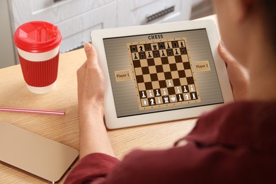Image of Woman playing online chess on tablet indoors, closeup