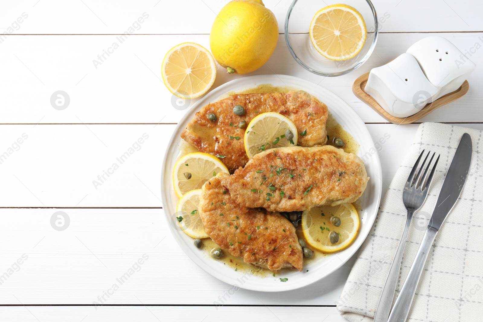 Photo of Delicious chicken piccata served on white wooden table, flat lay. Space for text