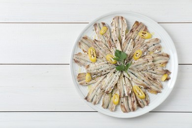 Tasty pickled anchovies with spices on white wooden table, top view. Space for text