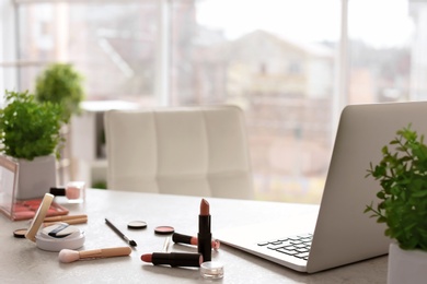 Photo of Makeup products for woman and laptop on table