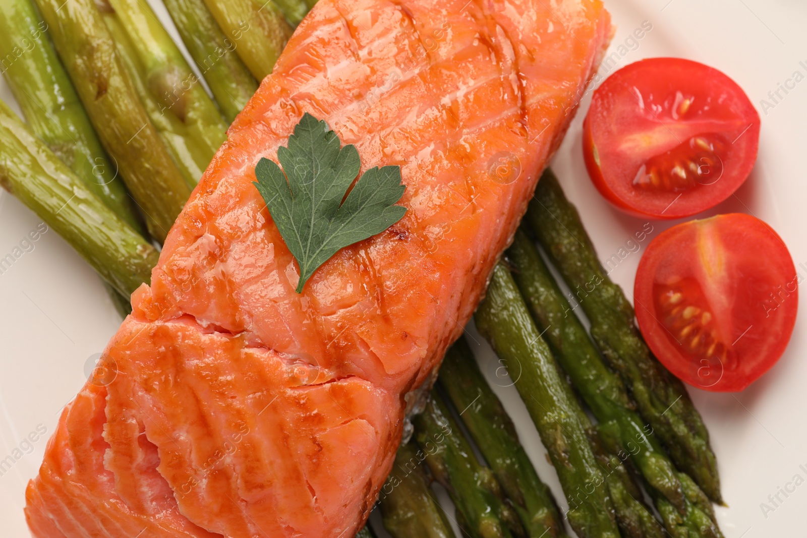 Photo of Plate with tasty grilled salmon, tomatoes and asparagus, top view