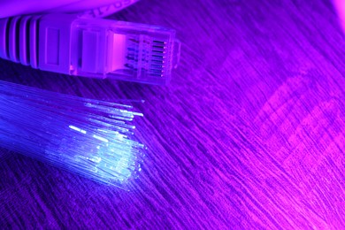 Optical fiber strands transmitting color light and cable with modular connector on table, closeup. Space for text