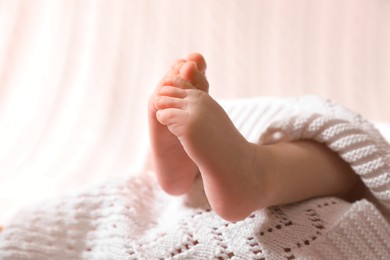 Photo of Cute newborn baby covered on white knitted plaid, closeup of legs. Space for text