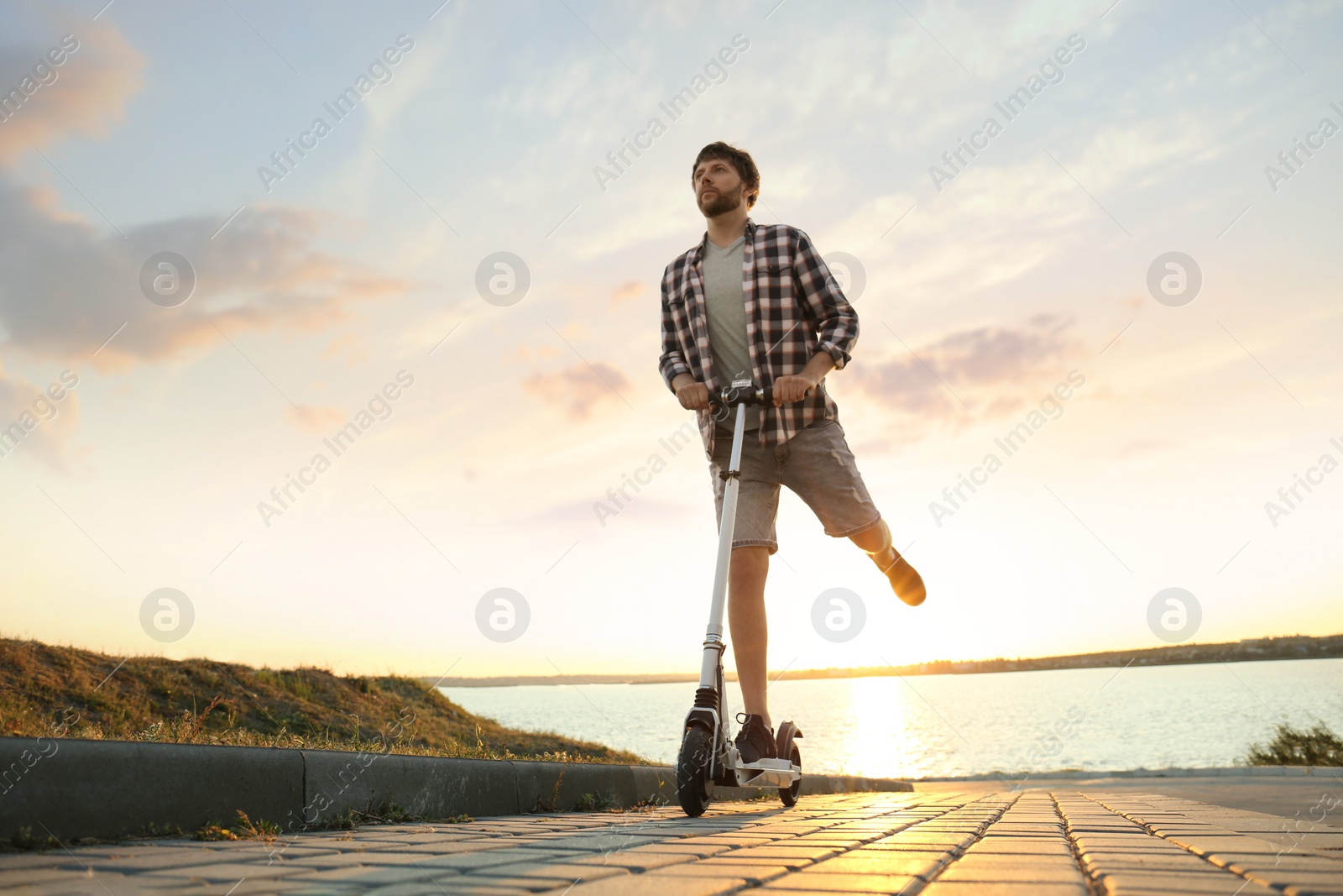 Photo of Man riding modern kick scooter on city street