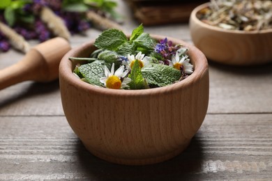 Mortar and different healing herbs on wooden table, closeup