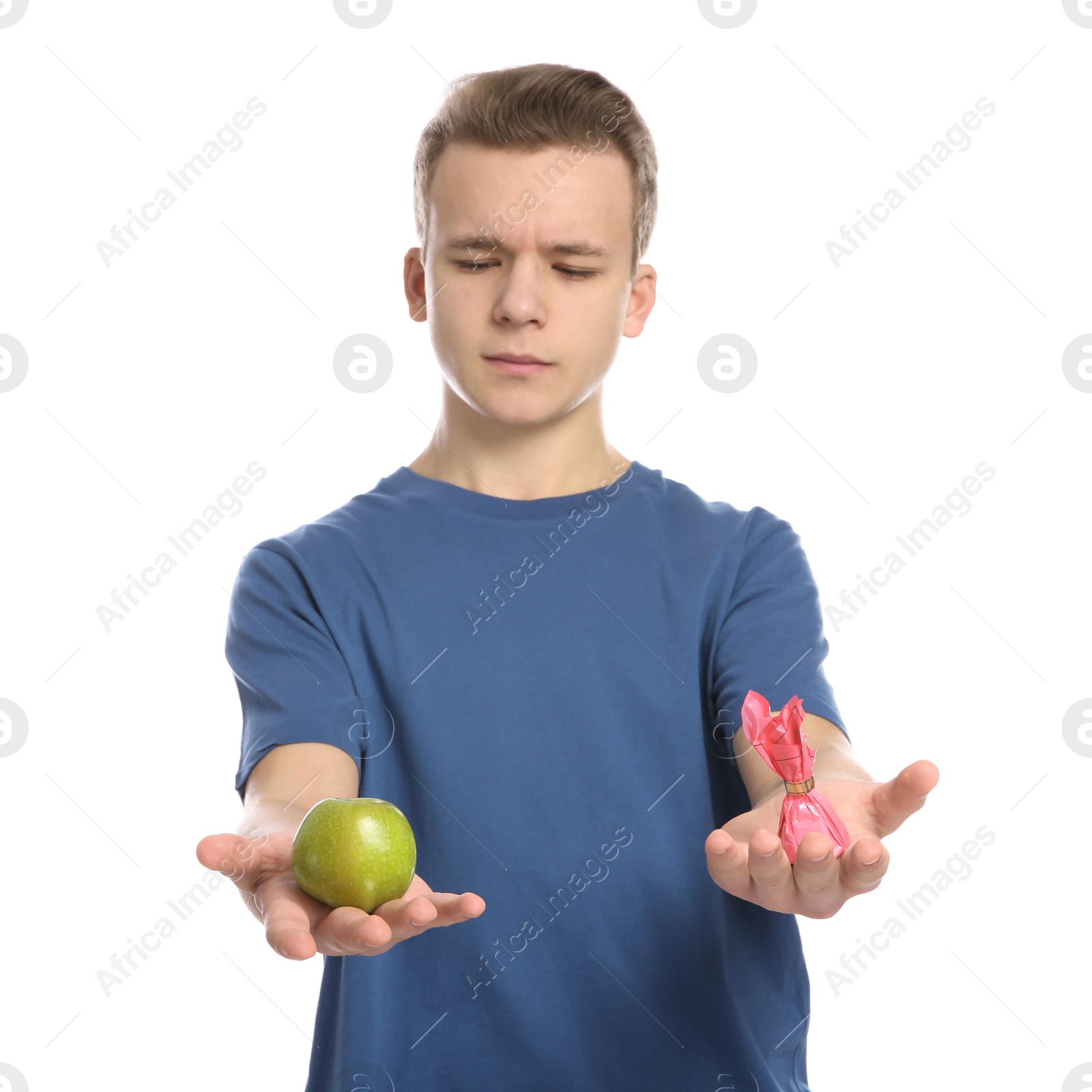 Photo of Teen boy with apple and candy on white background. Diabetes diet