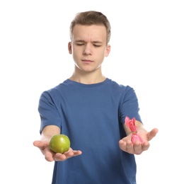 Photo of Teen boy with apple and candy on white background. Diabetes diet