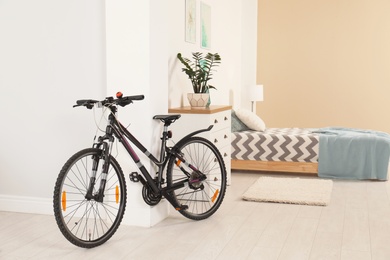 Bicycle near light wall in stylish room interior