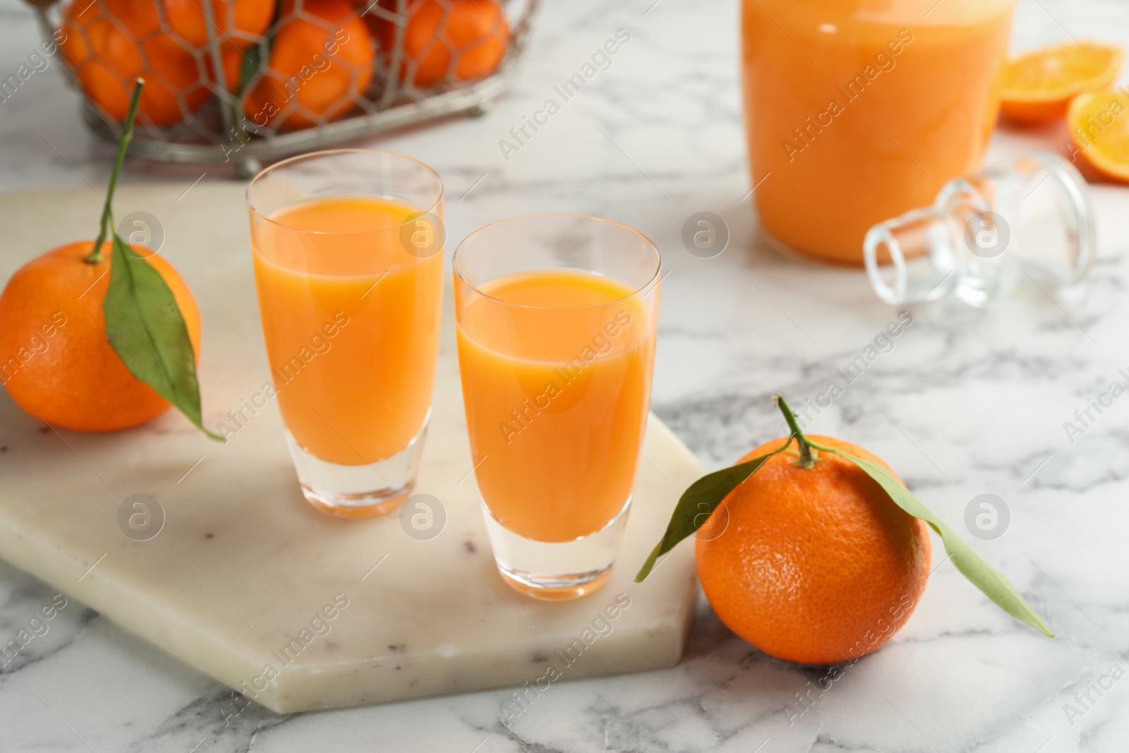 Photo of Delicious tangerine liqueur and fresh fruits on white marble table