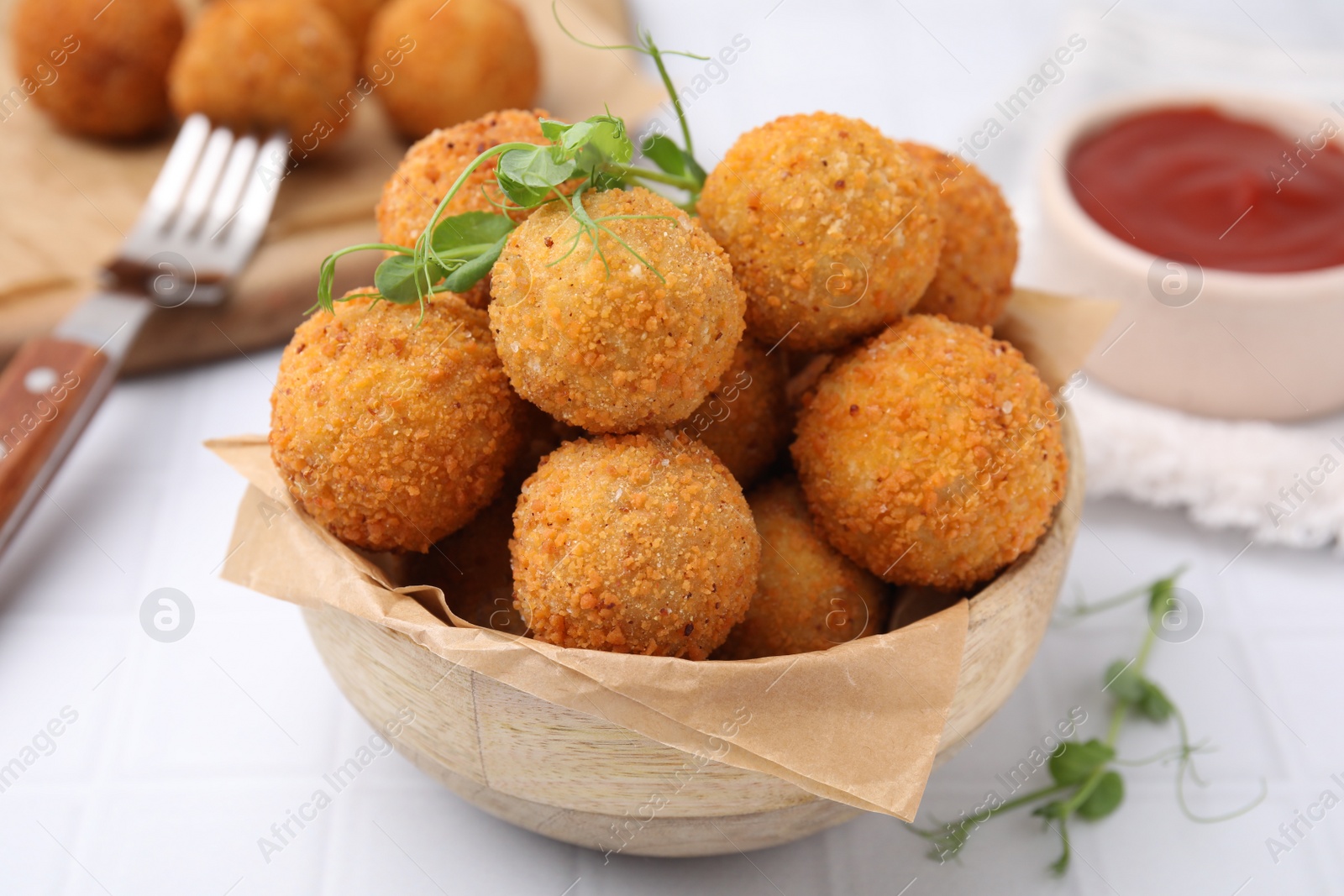 Photo of Bowl of delicious fried tofu balls with pea sprouts on white tiled table