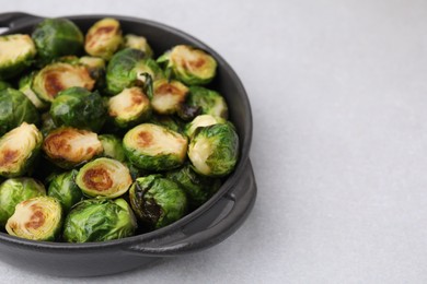 Photo of Delicious roasted Brussels sprouts in baking dish on light table, closeup. Space for text