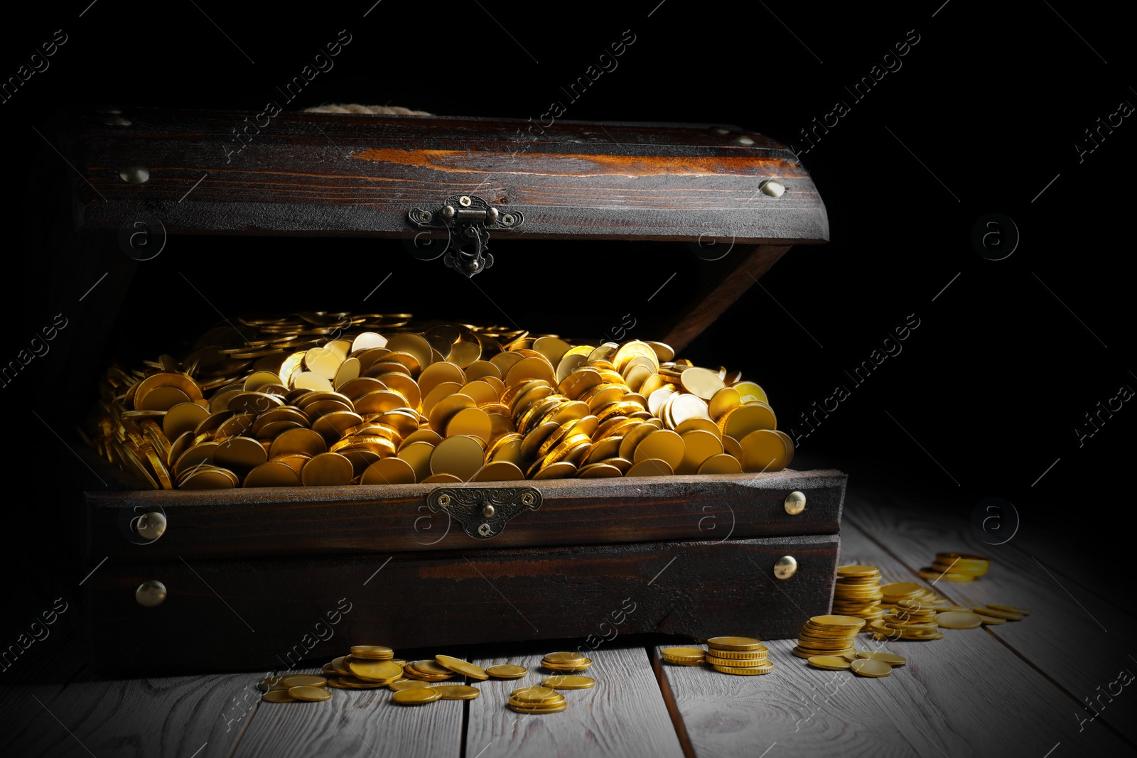 Image of Open treasure chest with gold coins on grey wooden table
