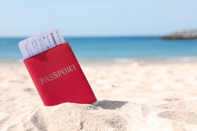 Photo of Passport with airline ticket in sand on beach. Space for text