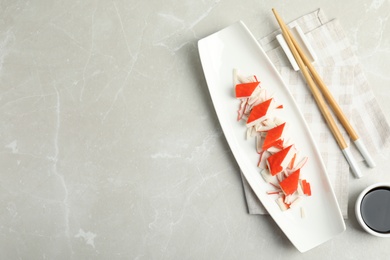 Photo of Fresh delicious crab sticks with soy sauce served on marble table, space for text