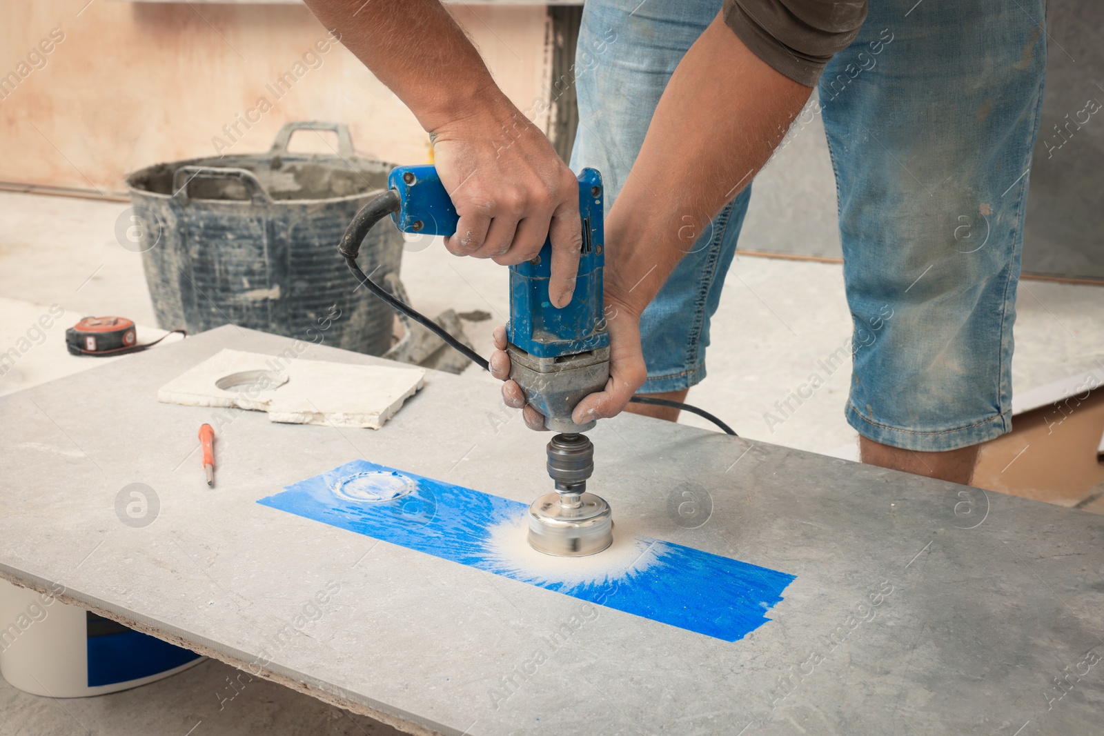 Photo of Worker making socket hole in tile indoors, closeup