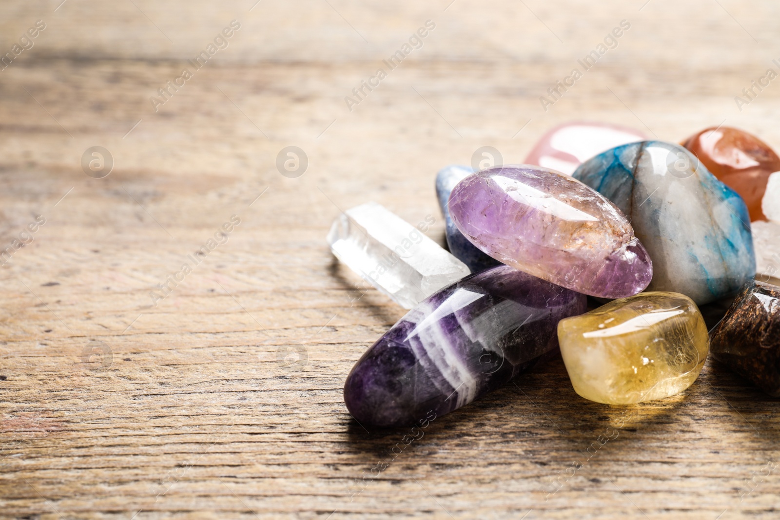 Photo of Different gemstones on wooden table, space for text